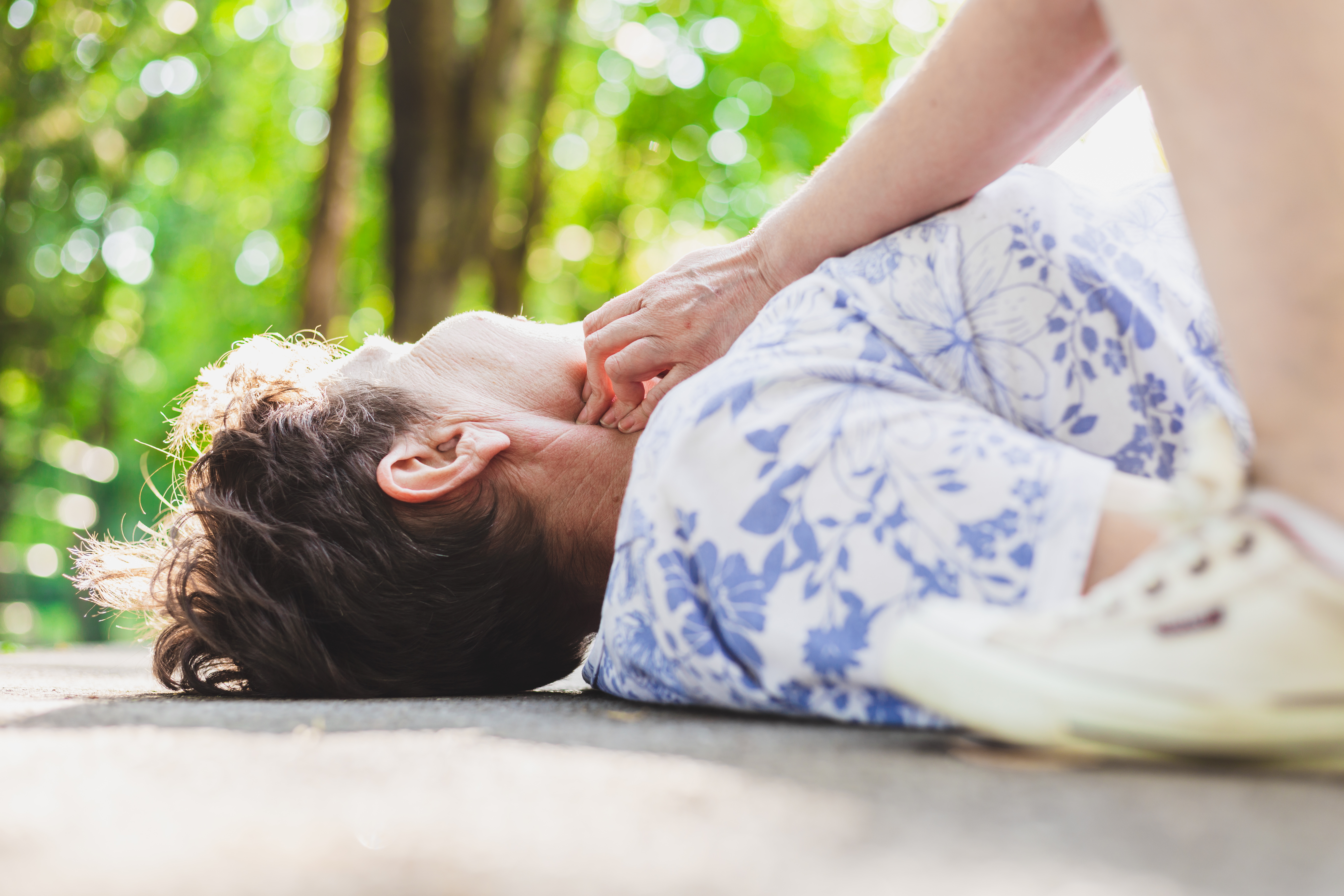Elderly woman on the ground getting her pulse checked