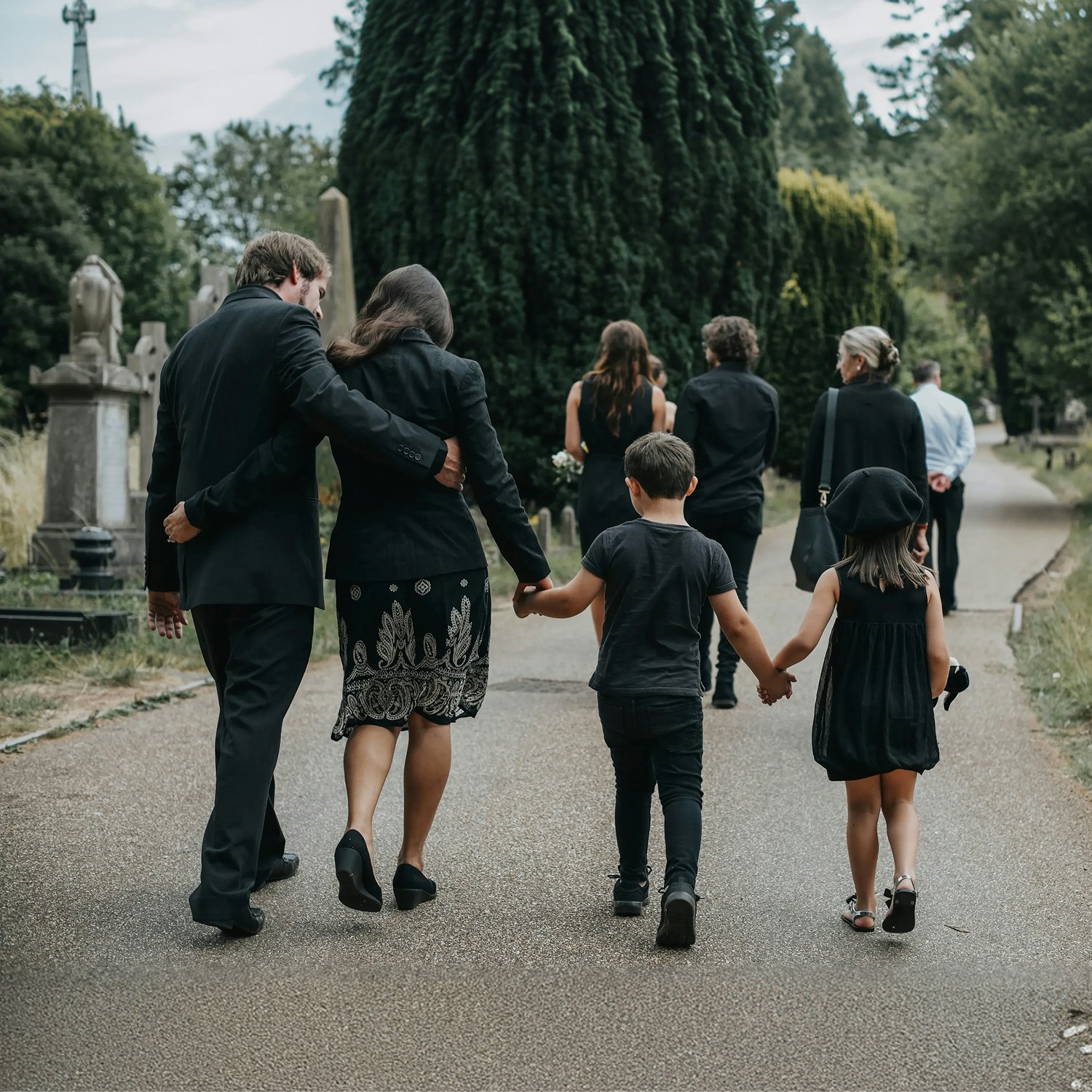 Grieving family walking through cemetery