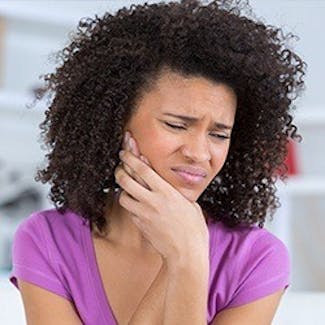 woman holding jaw in pain