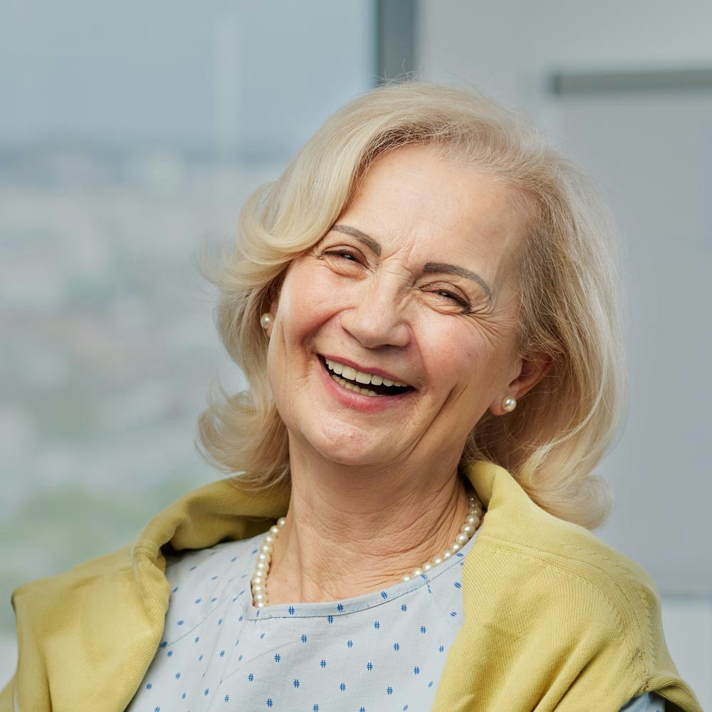 Mature smiling woman with a yellow sweater and dental bridges