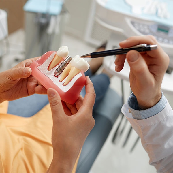 Dentist showing patient a model of a dental implant