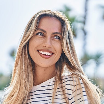 Young woman with a beautiful smile against palm trees