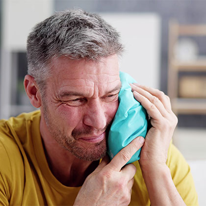 Man with ice pack against his face while he is in severe pain