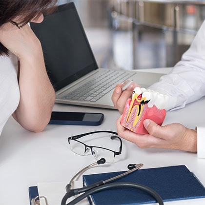 Dentist showing patient model of an infected tooth
