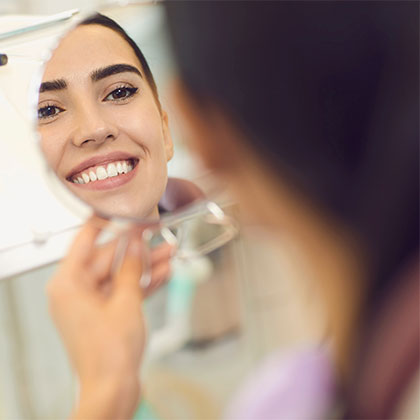 Woman smiling in mirror in dental chair