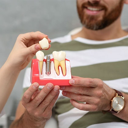 Dentist showing patient implant-supported crown model