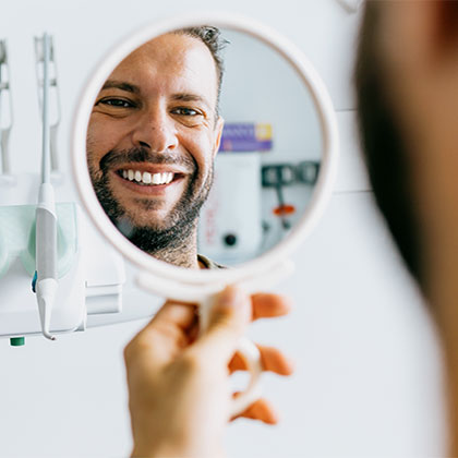Man smiling in mirror at a dental office