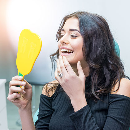 Woman checking her smile in the mirror at the dentist