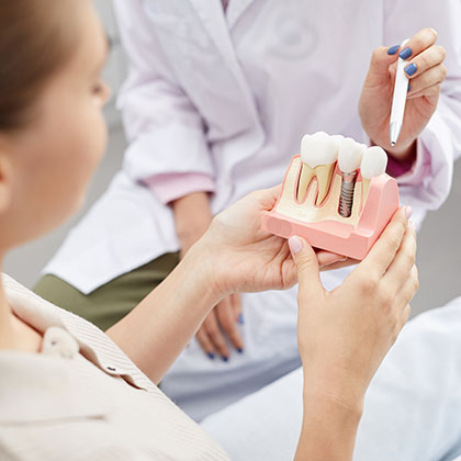 Dentist showing patient model of dental implant