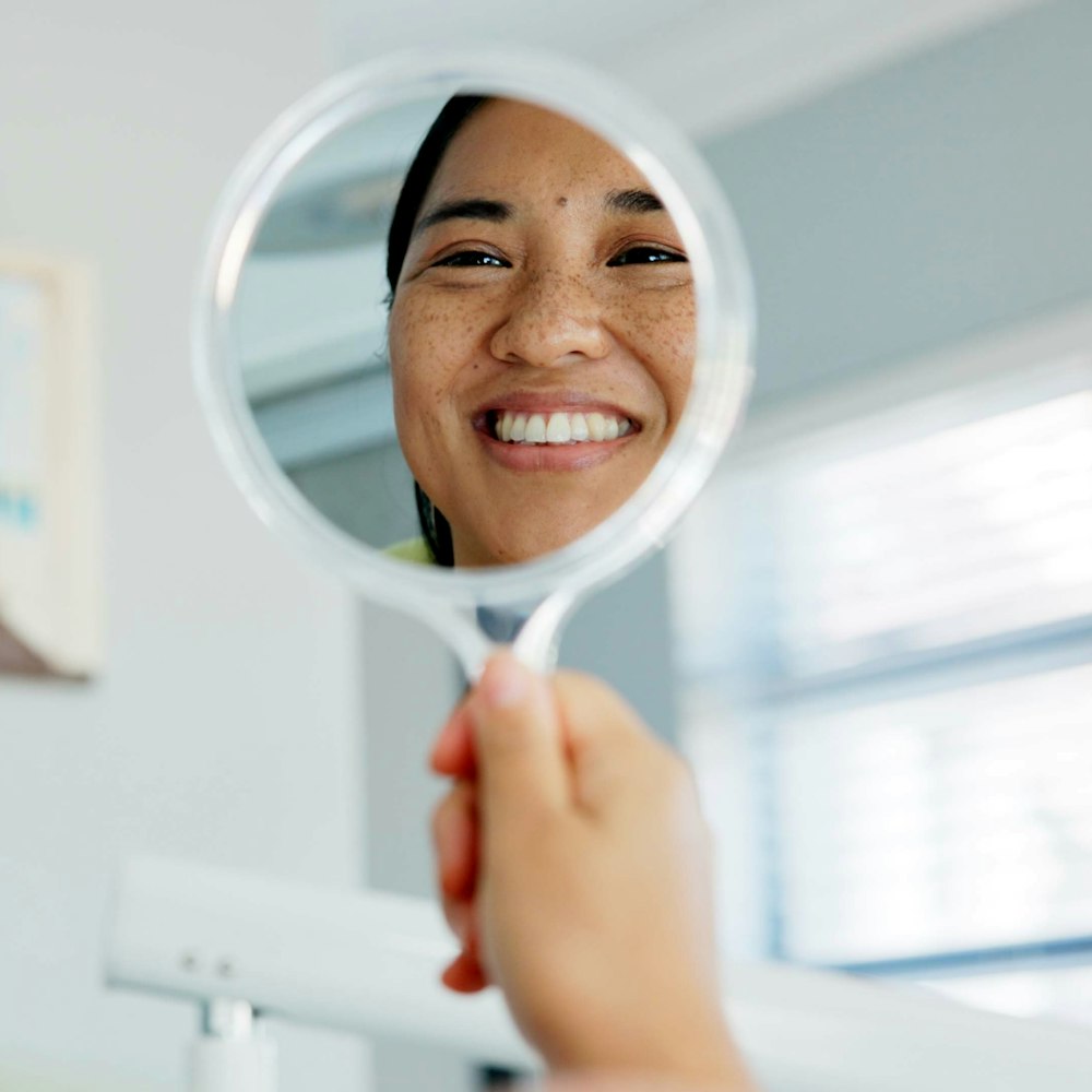 Woman smiling in the mirror at the dentist