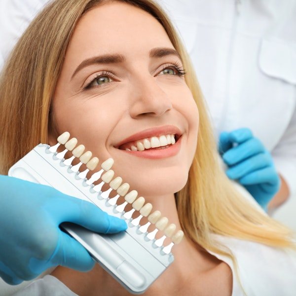 Woman in dental chair getting shade matched by veneers