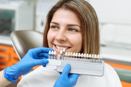 Dentist comparing tooth shades to a patient's smile