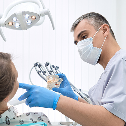 Dentist explaining dental crowns and pointing inside patient's mouth