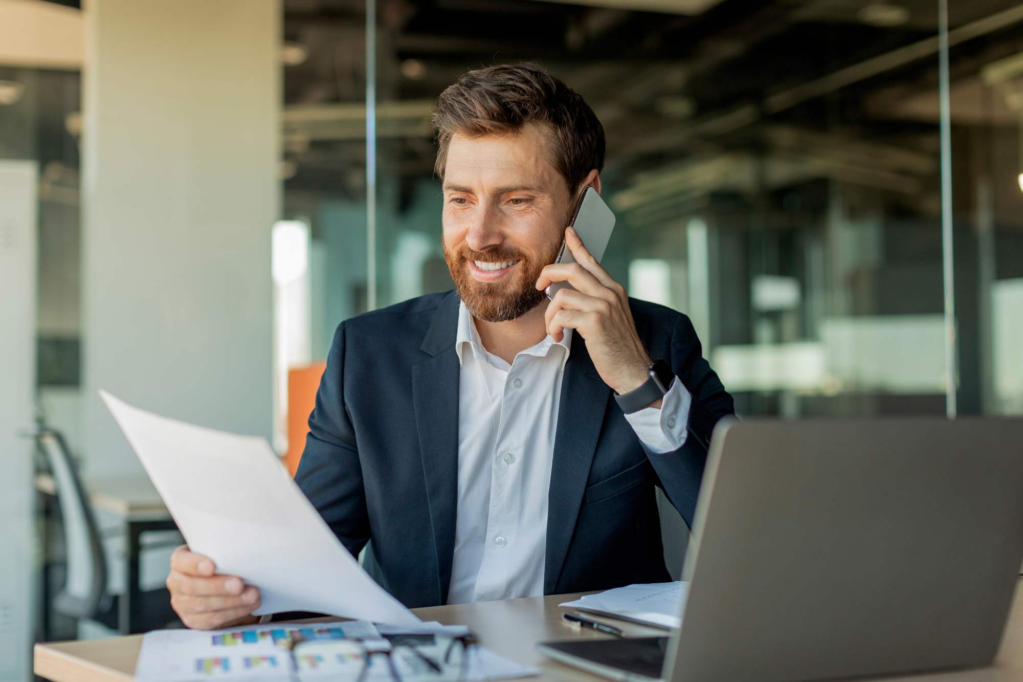 Business man looking through documents on a phone call