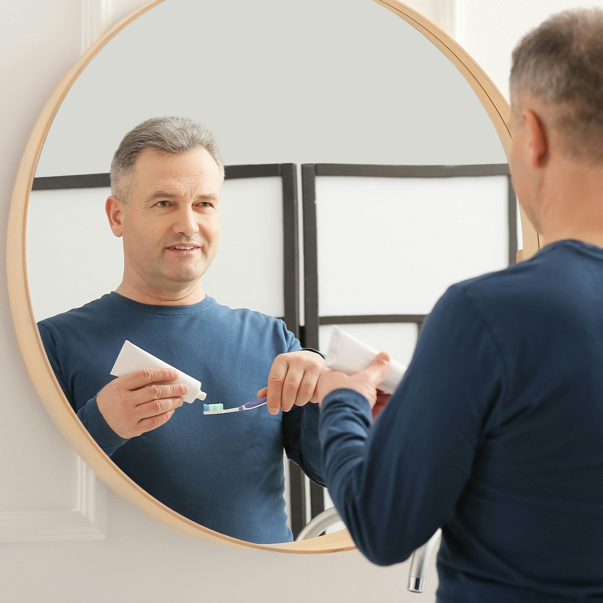 woman brushing teeth in the mirror
