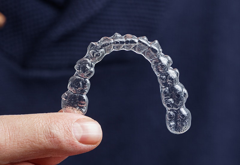 a man holding an Invisalign aligner tray