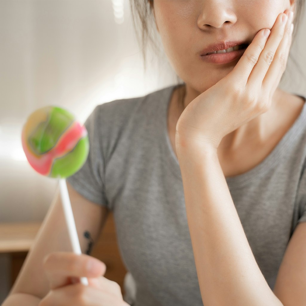 woman with a toothache holding candy