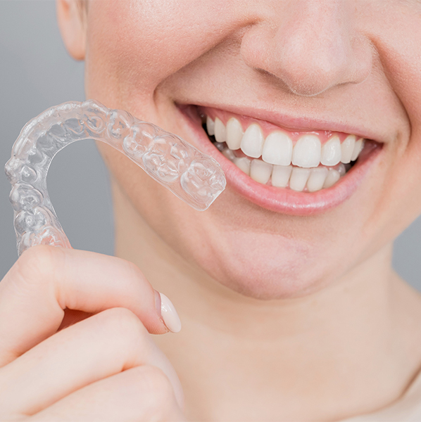 person smiling while holding a clear aligner