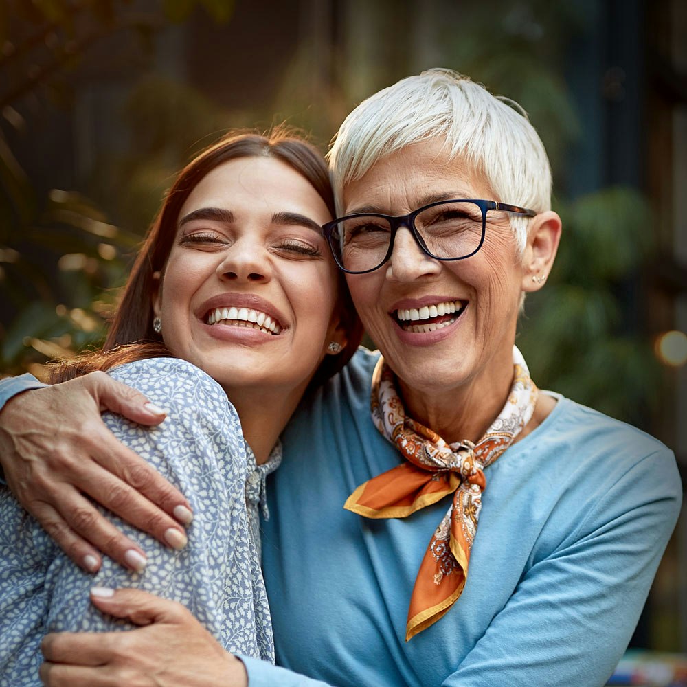 smiling mature woman hugging a younger woman