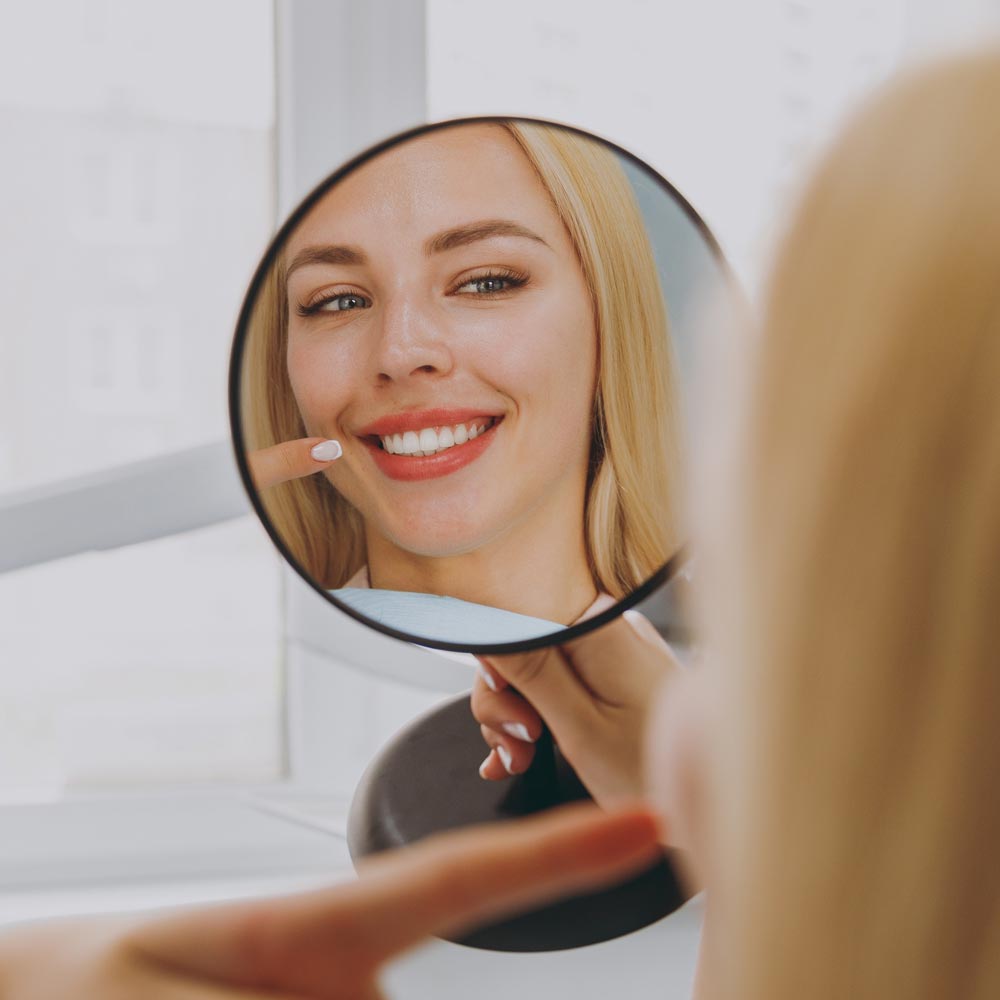 woman smiling at self in mirror