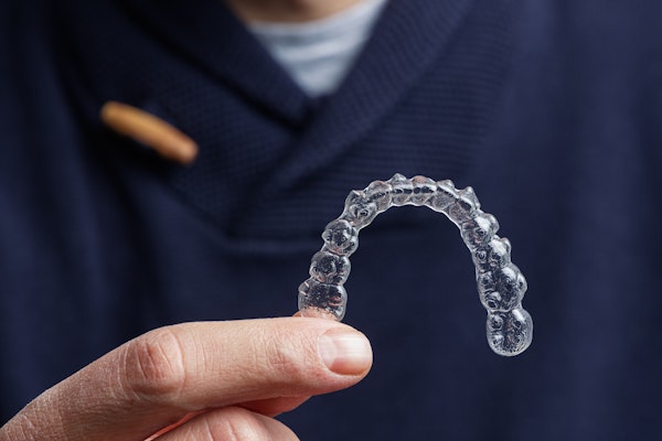 a hand holding an Invisalign aligner