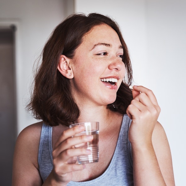 A woman taking a pill at home