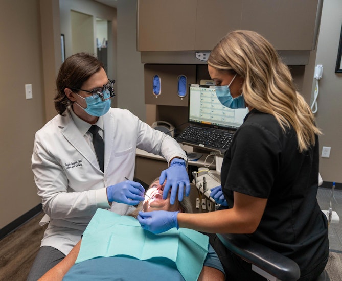 our dentist and dental assistant working with a patient