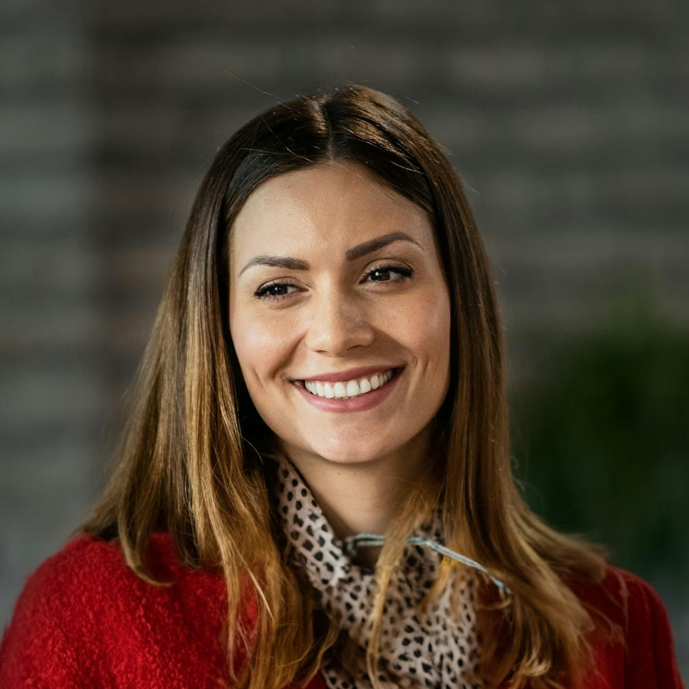 Smiling woman after laser dentistry wearing red talking to someone