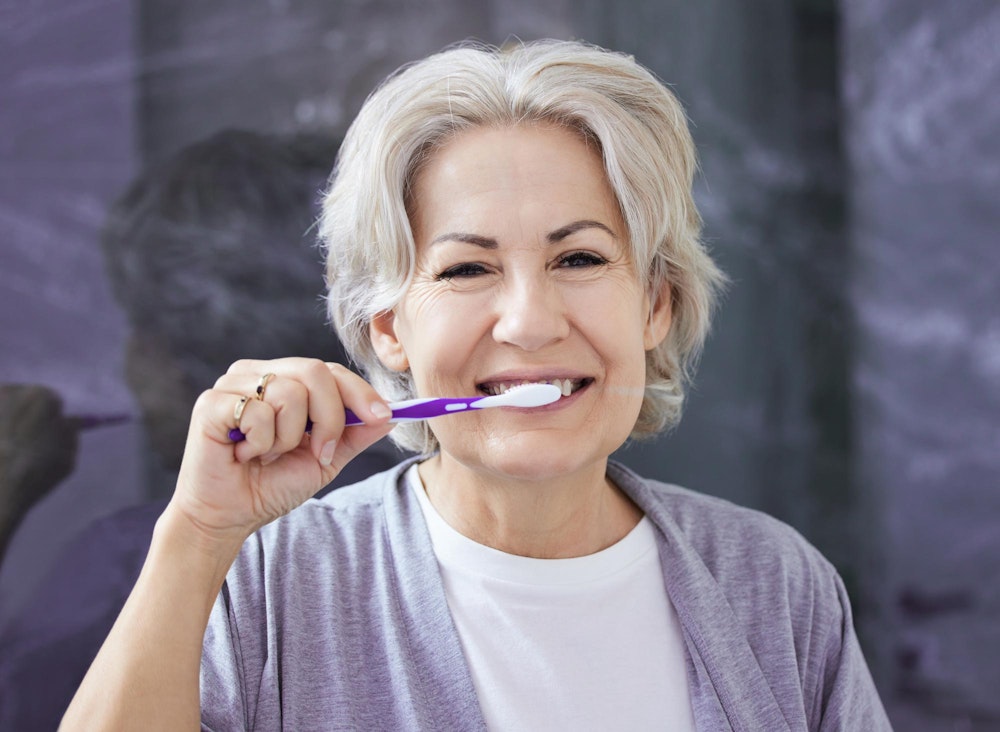 Woman brushing teeth in mirror