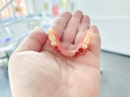 Hand holding a set of partial dentures