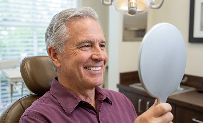 senior man admiring his smile in a mirror