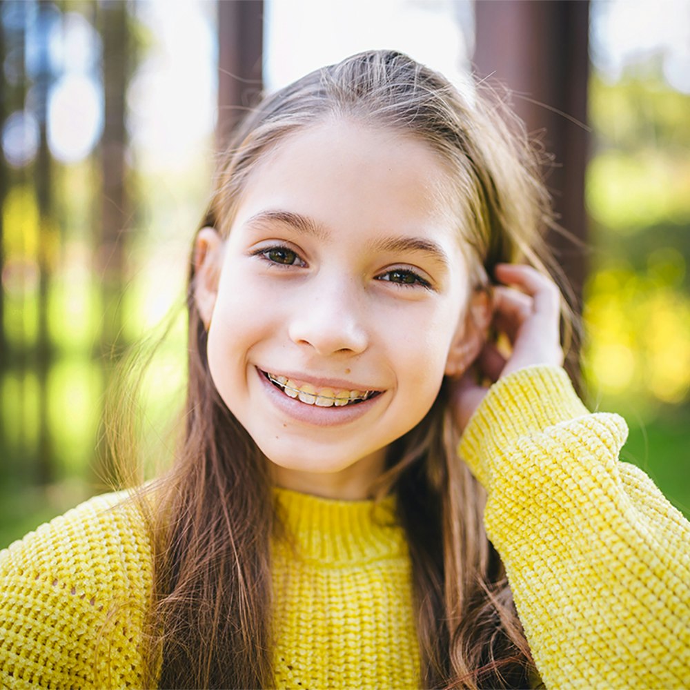 Young girl smiling in a park with braces