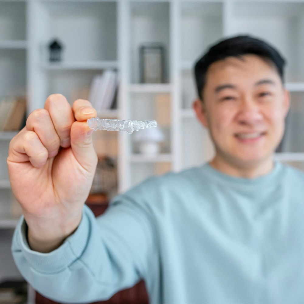 Man holding out his invisalign aligner