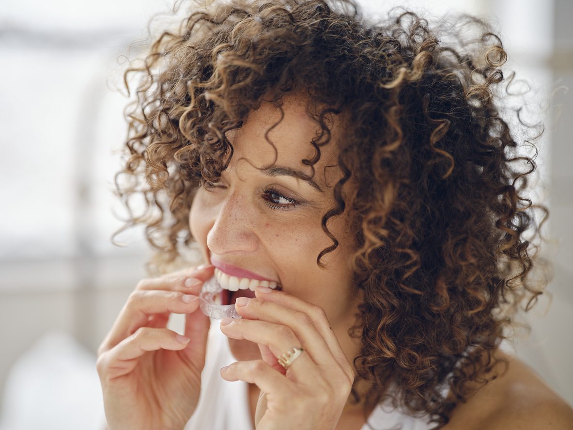 happy-looking woman putting clear aligners in