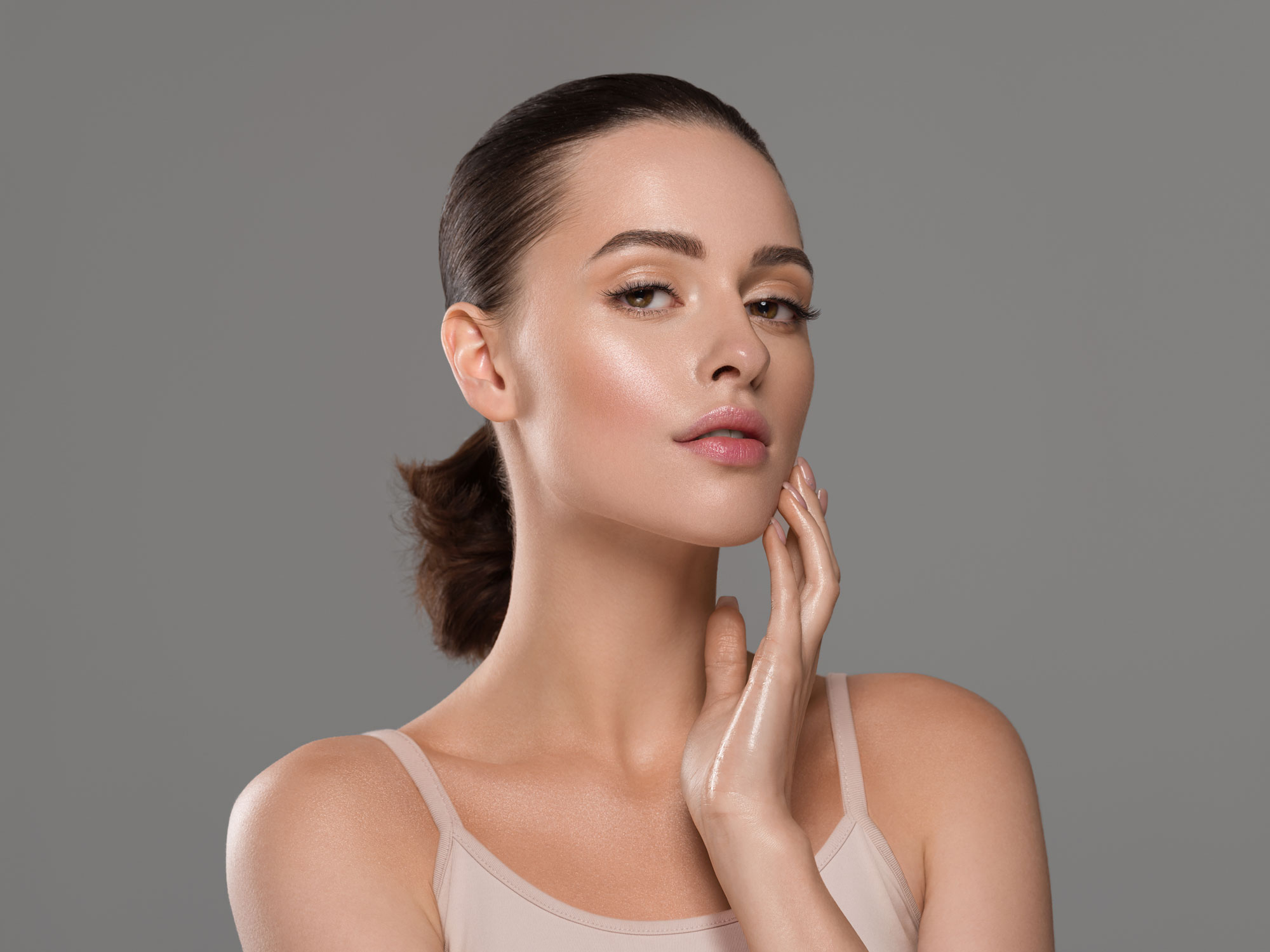 Smiling woman with clear skin touching her cheek, showcasing healthy and radiant complexion.