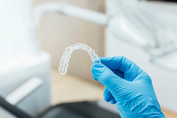 Dentist's hand holding SureSmile aligner