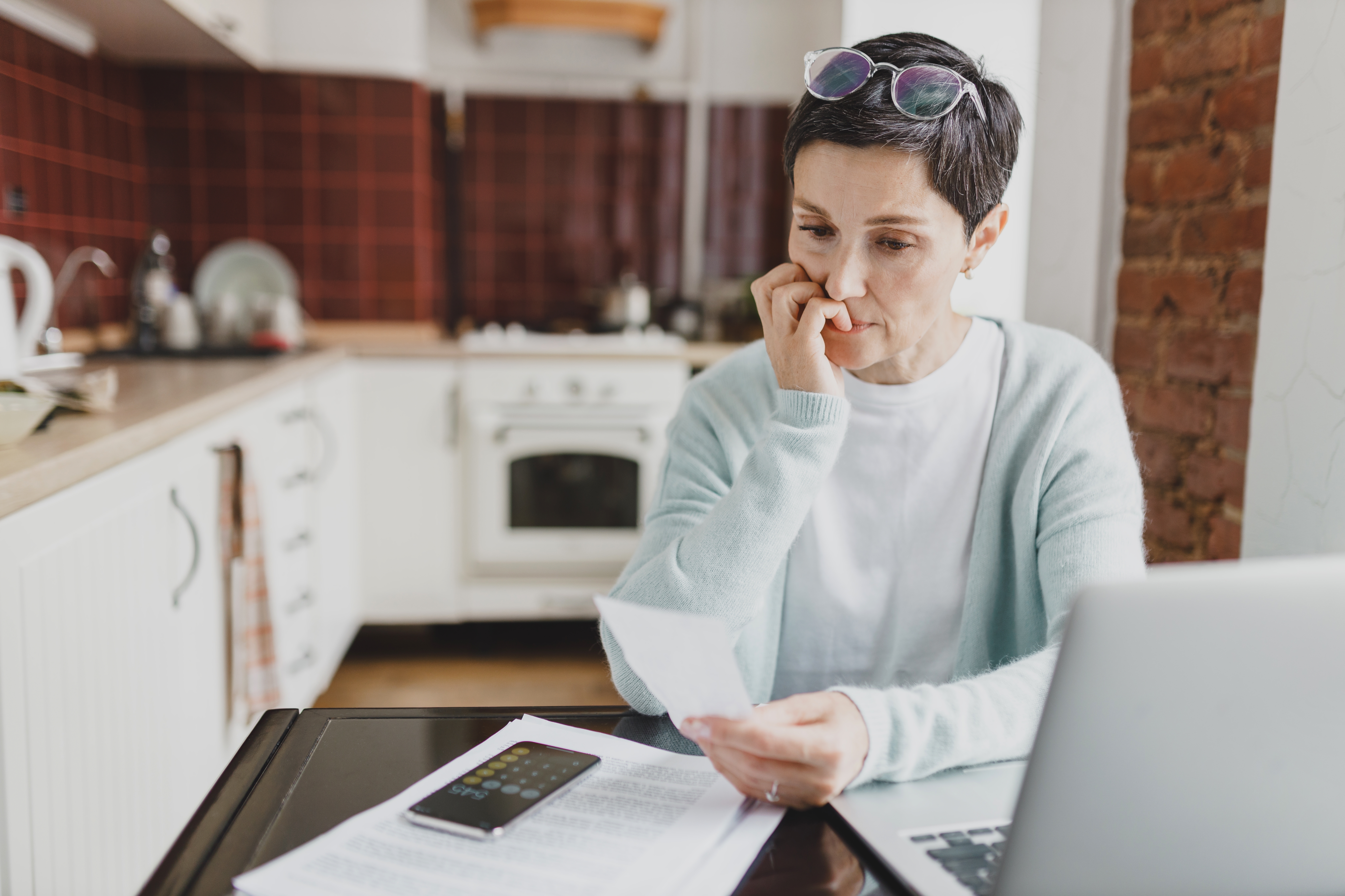 Woman biting nails while looking at bills