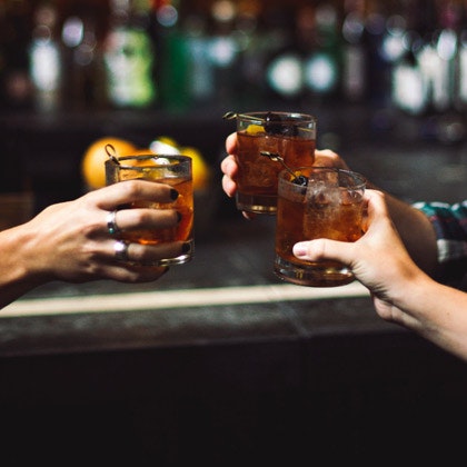 Patrons clinking glasses in a cocktail bar