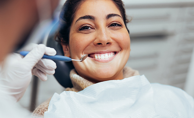 Cosmetic dentist checking a smiling patient's teeth and gums
