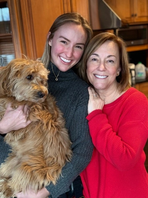 Older woman and younger woman smiling with dog.
