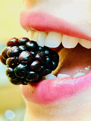 close up image of someone hold a blackberry in their teeth