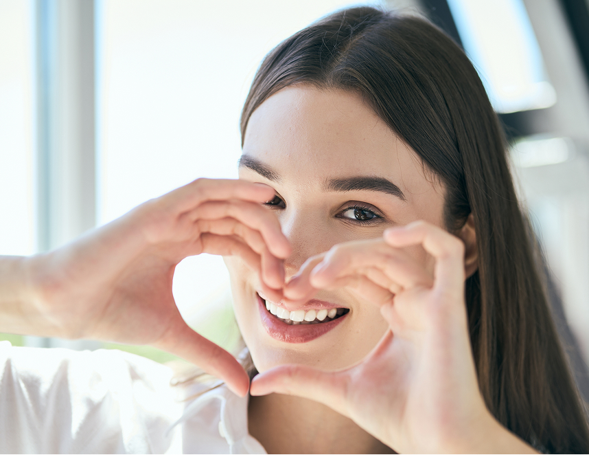 woman making heart with hands in front of smile