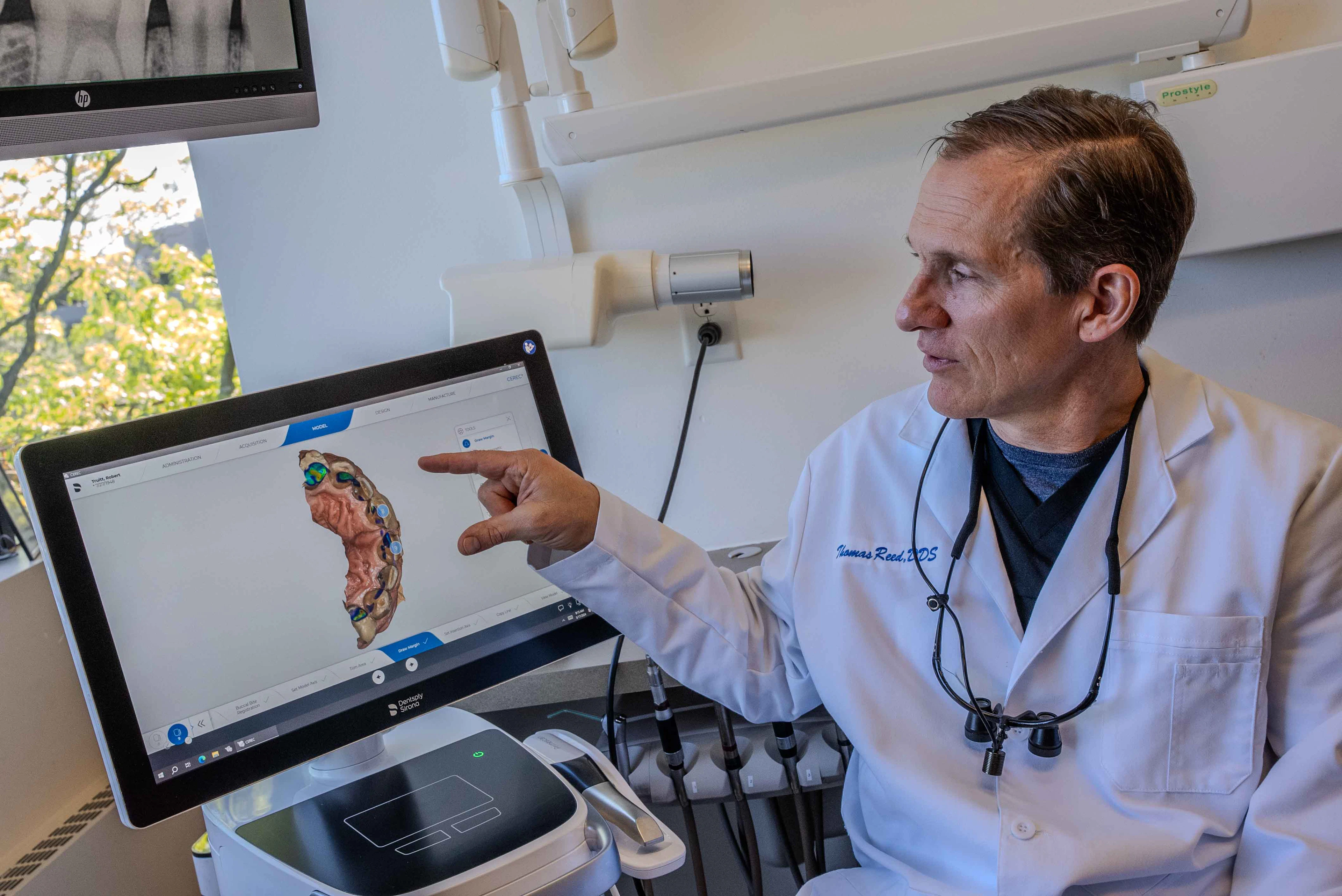 Thomas Reed DDS pointing at Densply Sirona 3D model of teeth