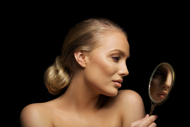 Woman looking in mirror after Juvederm Voluma treatment