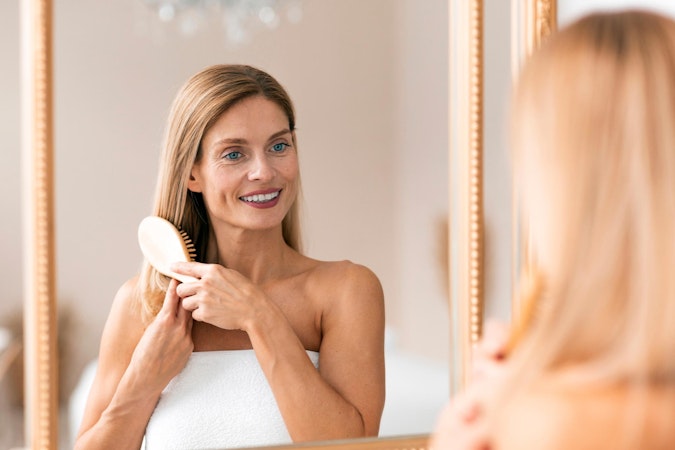 Woman brushing thick hair in the mirror and smiling