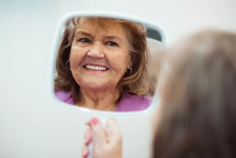 NuSmile patient smiling in a mirror
