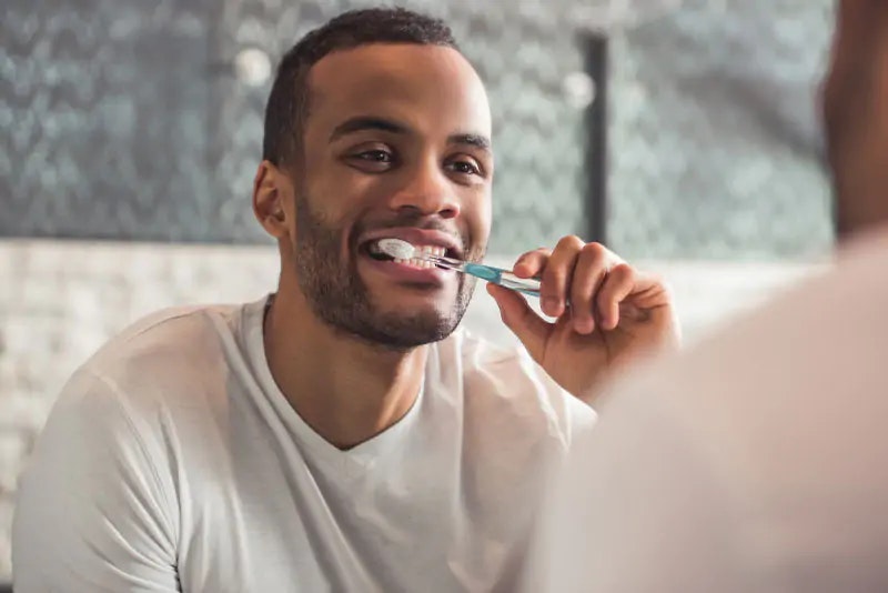 Man brushing his teeth in the mirror