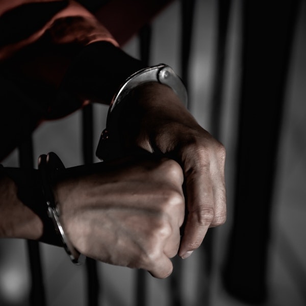 hands in handcuffs behind bars