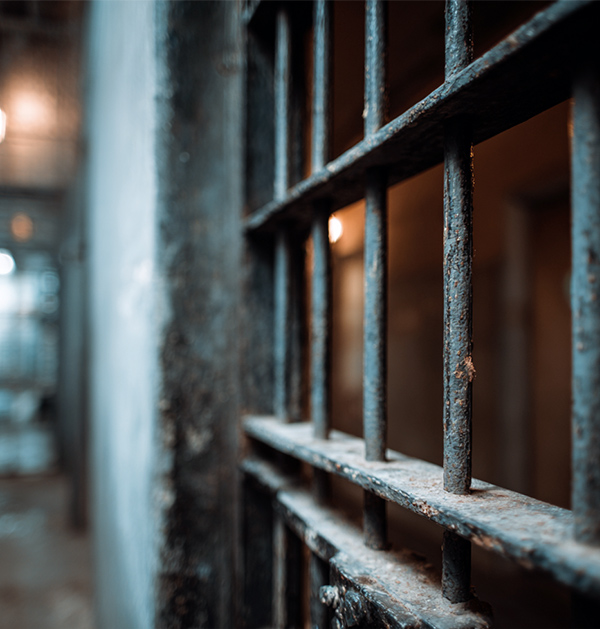 Close-up view of rusty prison bars in a dimly lit jail corridor