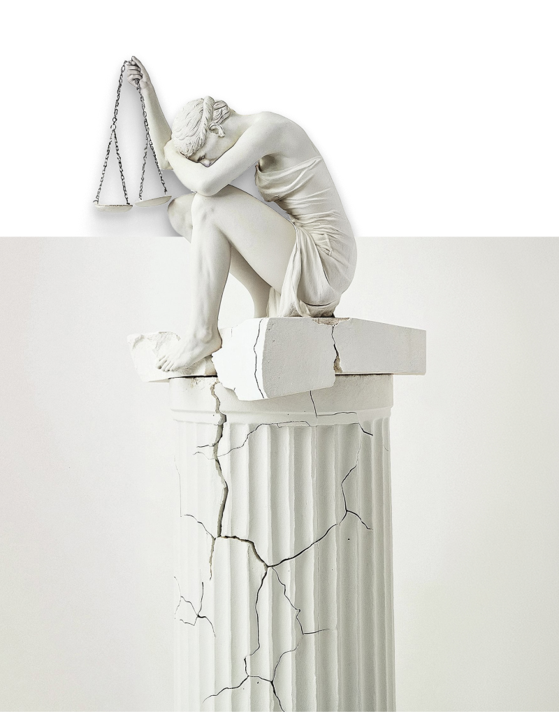 A statue holding a justice scale on top of a cracked pillar